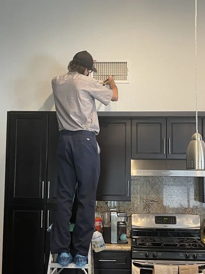 Technician inspecting an air vent during HVAC service in Isanti